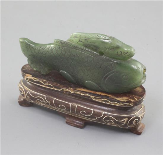 A Chinese spinach green jade double fish snuff bottle, 19th century or earlier, length 6.4cm, later wood stand